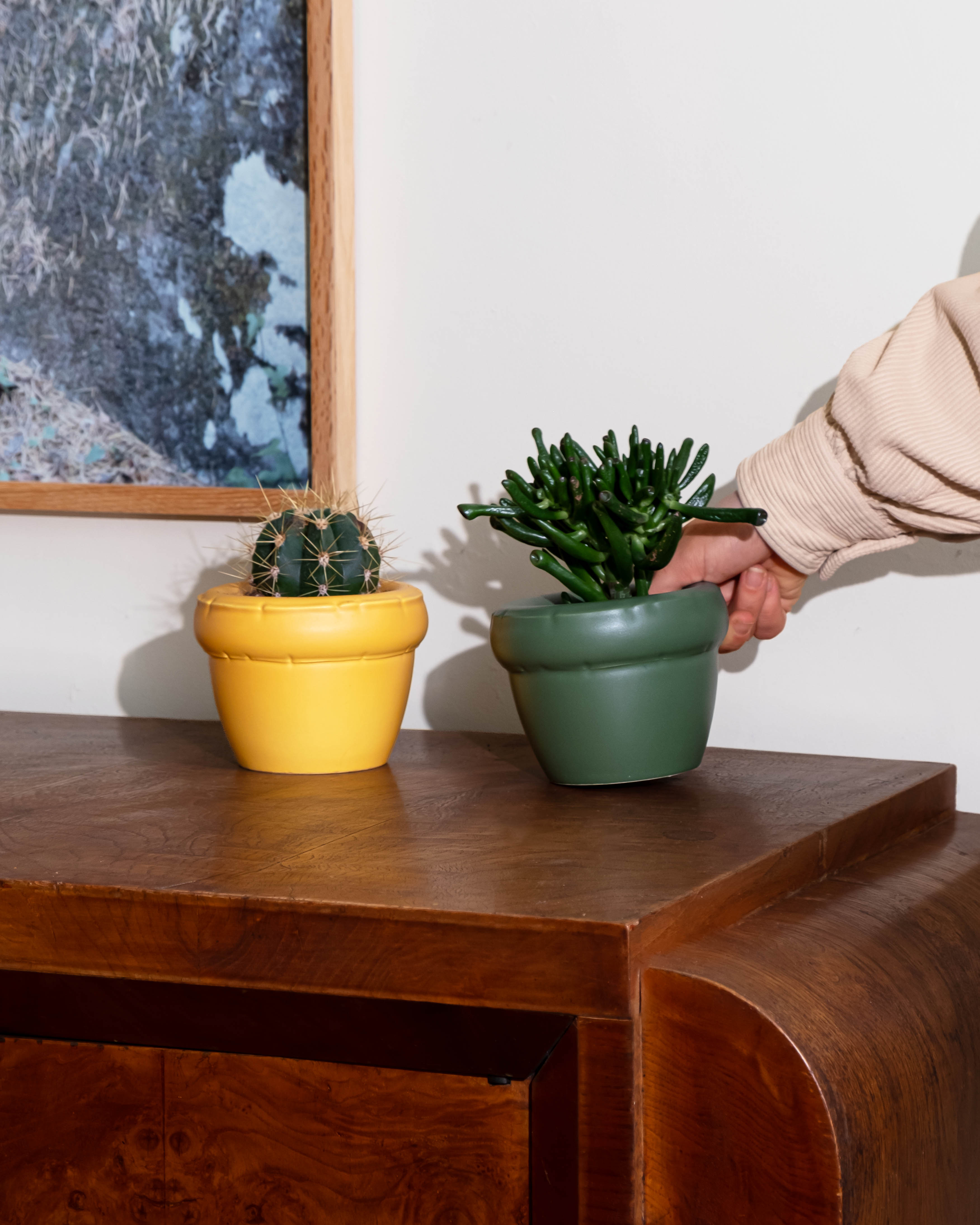 2x Small planter 'LOUIS' on a wooden surface with a person's hand reaching towards one of them.